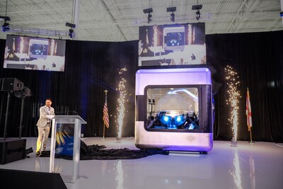 AMPERA Founder and CEO Brian Matthews pulls curtain revealing the first full-scale 3D printed reactor module, featuring a fully 3D printed silicon carbide reactor core and reactor pressure vessel at a celebratory event at the company’s innovation center in Palm Beach Gardens, Fla. (PRNewsfoto/AMPERA)