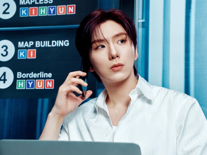 Kihyun in a white shirt sitting at a desk with a laptop, holding a phone to their ear, looking thoughtfully at a sign with different project names.