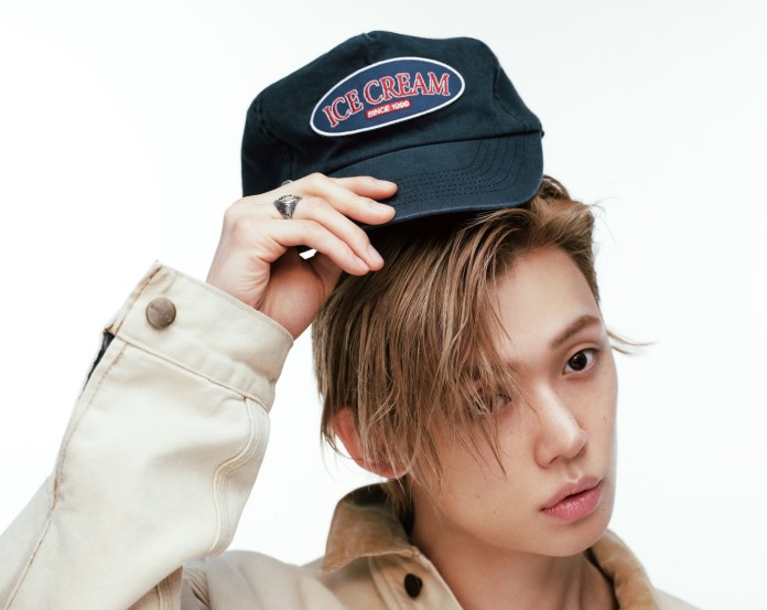 Yeonjun with light brown hair wearing a cream-colored jacket and holding a navy cap embroidered with 'ICE CREAM' in red.