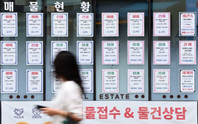 Real estate listings displayed on a window, featuring various properties for sale and rent, with prices and details clearly posted.