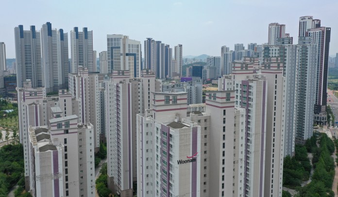 Aerial view of a modern urban area featuring tall residential buildings and skyscrapers under a clear sky.