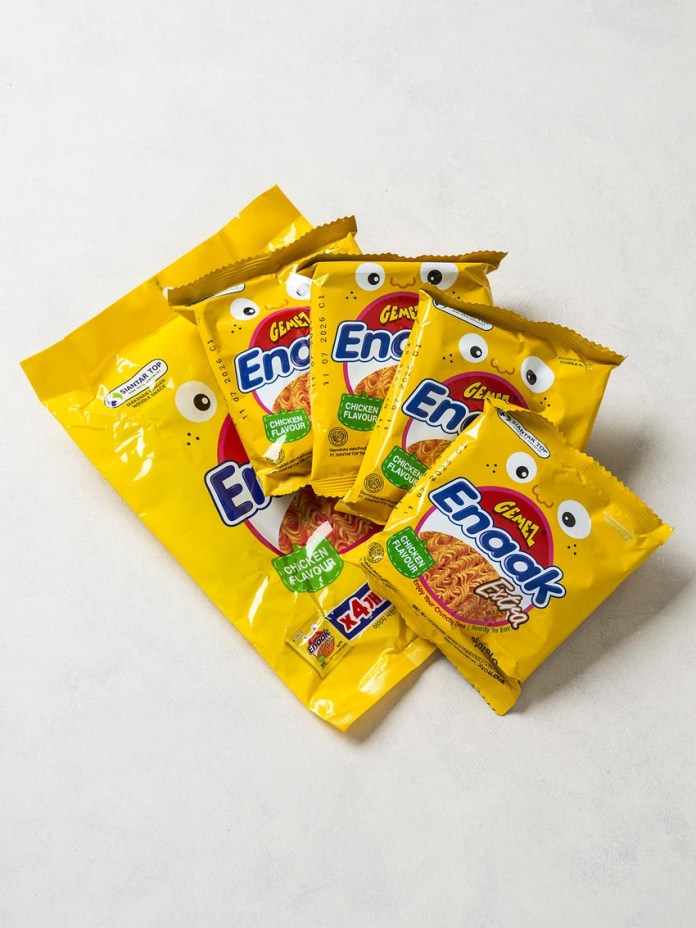 A collection of yellow packaging for Enoak chicken-flavored instant noodles, featuring cartoonish eyes and a playful design, arranged on a light grey surface.