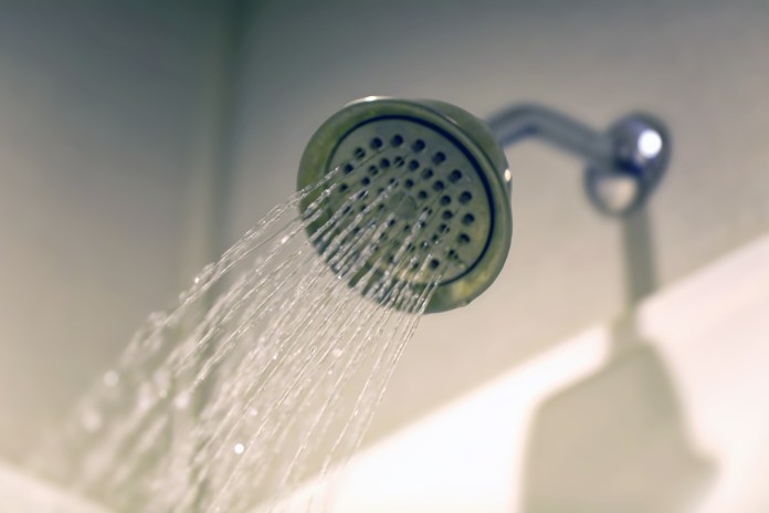 Close-up of a showerhead with water streaming down.