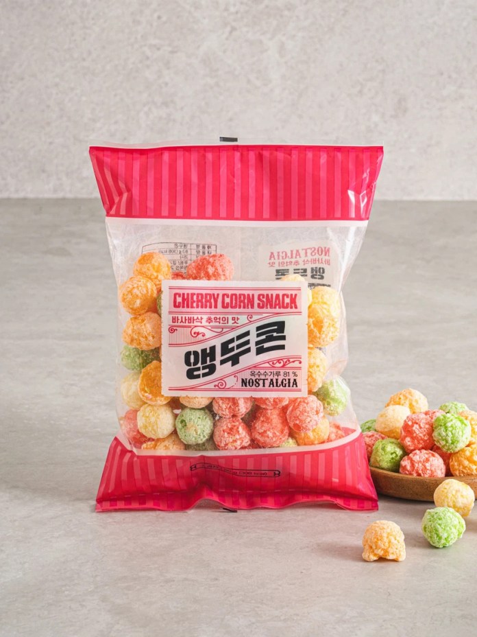 A bag of cherry-flavored corn snack featuring colorful popcorn-like balls in various shades of orange, yellow, and green, with a nostalgic design and Korean text on the packaging.