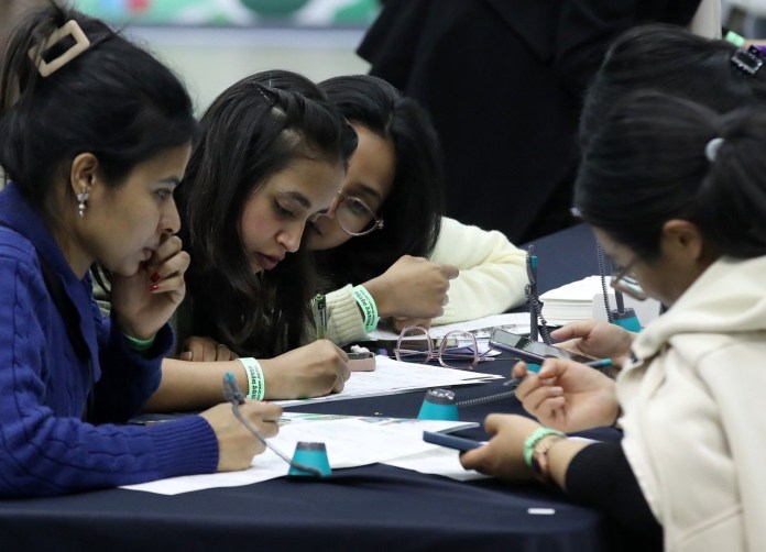 A group of students focused on their work at a table, taking notes and discussing ideas.