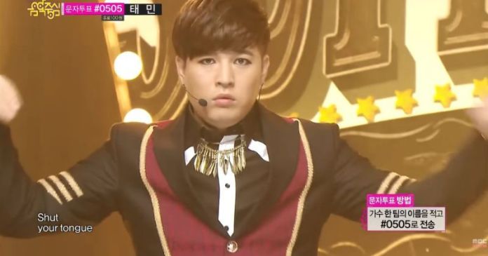Super Junior Shindong on stage wearing a stylish outfit with a decorative collar, striking a serious pose during a performance.