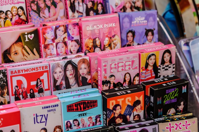 Display of various K-pop merchandise boxes featuring different idol groups, including BTS, BLACKPINK, and others, arranged in colorful packaging.