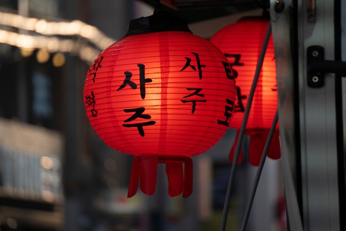 Close-up of illuminated red lanterns with black calligraphy against a blurred background.
