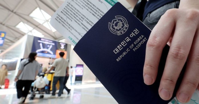 A person holding a South Korean passport with boarding passes in an airport terminal.