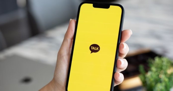 A hand holding a smartphone displaying a yellow screen with the word 'TALK' in a speech bubble.