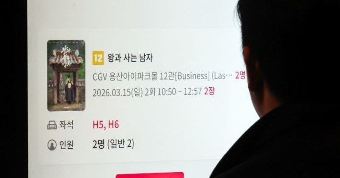 A person viewing a digital movie ticket reservation screen for a film titled 'The Man Who Lives with a King' at a CGV cinema, showing date, time, and seating details.