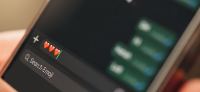 Close-up of a smartphone screen displaying a chat interface with emoji options, including heart emojis.