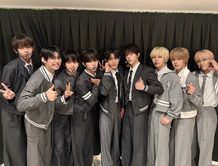 AHOF dressed in matching gray outfits posing together for a photograph with various hand signs and expressions in front of a black curtain.