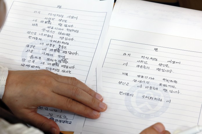 An individual holding two open notebooks with handwritten text in Korean, featuring personal messages and reflections.