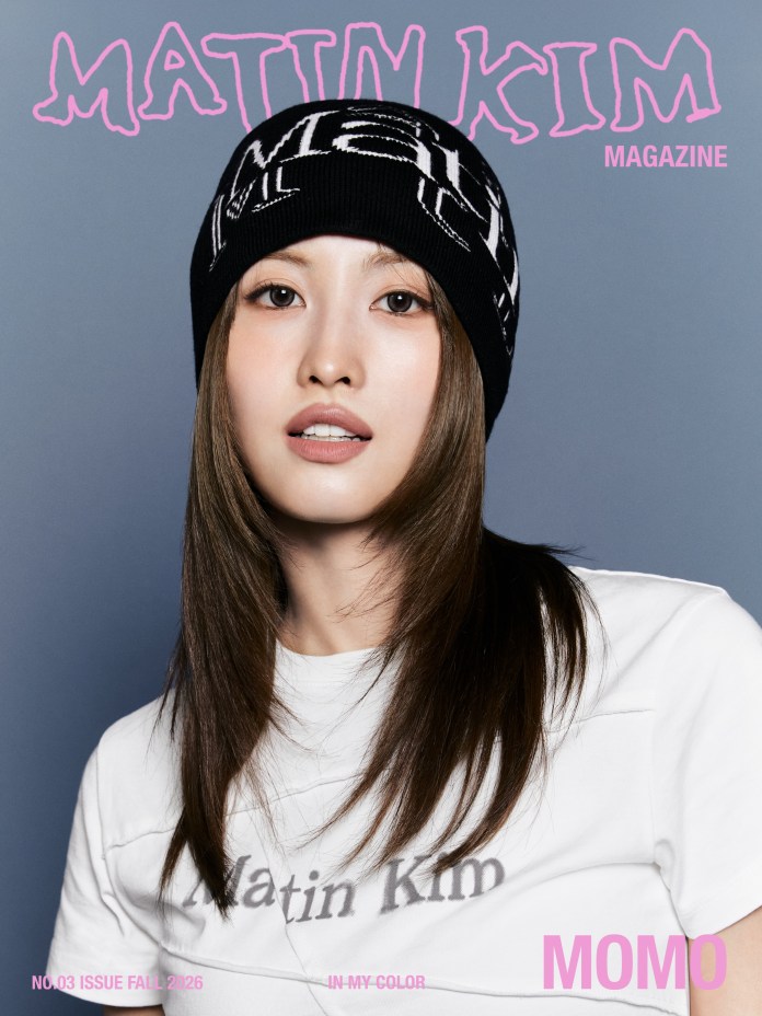 Close-up of Momo with long hair wearing a black beanie and a white shirt, appearing on the cover of a magazine titled 'Matin Kim.' The background is a soft gray, and the text on the cover includes 'MAGAZINE,' 'NO.03 ISSUE FALL 2026,' and 'MOMO.'