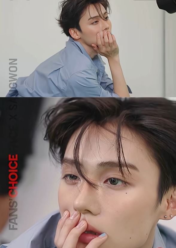 Sangwon with styled dark hair, wearing a light blue shirt, poses thoughtfully with their hand on his mouth, showcasing an expressive look.