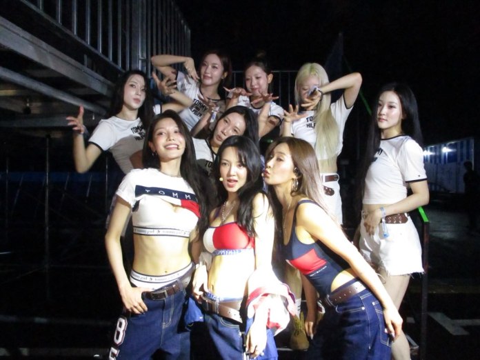 Sooyoung, Hyoyeon, and Yuri posing together in front of a dimly lit background, wearing casual outfits with crop tops and denim, showcasing lively expressions and playful poses.