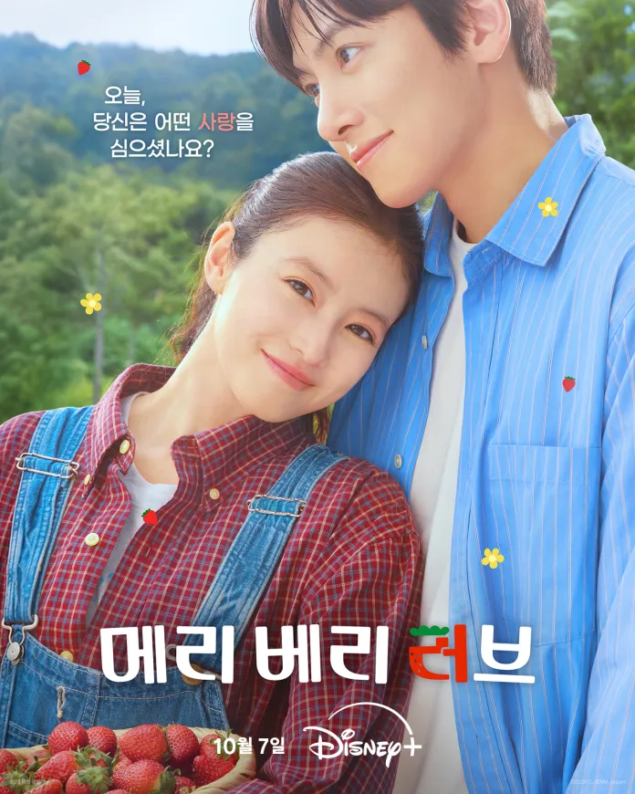 Ji Chang Wook and Imada Mio smiling together outdoors, surrounded by greenery and holding a basket of strawberries. Imada Mio has a plaid shirt and overalls, and Ji Chang Wook is wearing a blue shirt. Text in Korean above them promotes a show titled 'Mary Berry Love' with a release date of October 7 on Disney+.