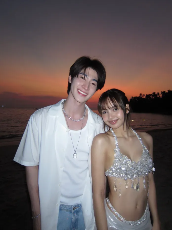 Lisa and Blue posing together on a beach at sunset, Blue wearing a white shirt and Lisa in a sparkling outfit.