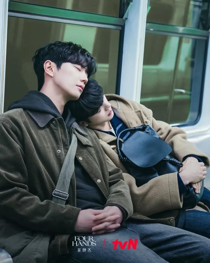 Song Kang and Lee Junyoung  sleeping on a train, Song Kang resting his head on the shoulder of Lee Junyoung. They are dressed in warm clothing and appear relaxed in their seats.