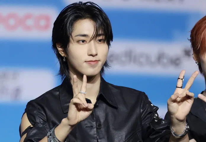 Stray Kids' Han in a black shirt making a peace sign with his right hand.