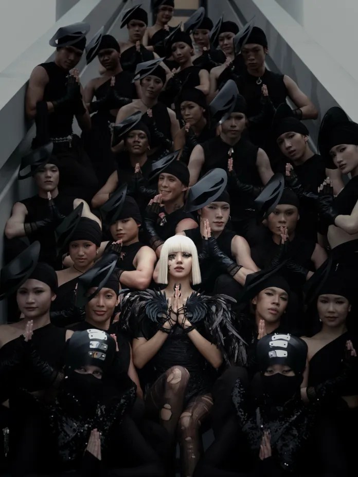 Lisa dressed in black attire, each with a distinct hat, posing together on stairs. The central figure, featuring white hair and unique costume elements, holds their hands in a prayer position, surrounded by others in similar poses.