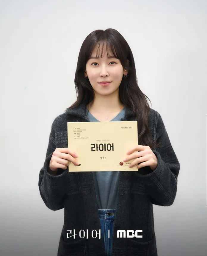 Seo Hyun-jin holding a script titled '라이어' in front of a plain background, wearing a black cardigan and a gray top.