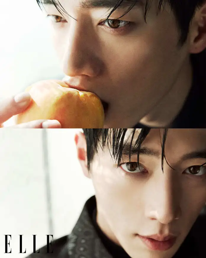 Seo Kang-joon with wet black hair, holding a peach close to his mouth, looking contemplative.
