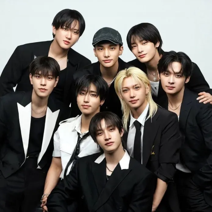 Stray Kids dressed in stylish outfits, posing together against a light background.