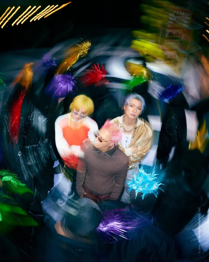 BIGBANG featuring three stylized individuals with colorful hairstyles surrounded by a swirl of abstract, bright shapes and colors.
