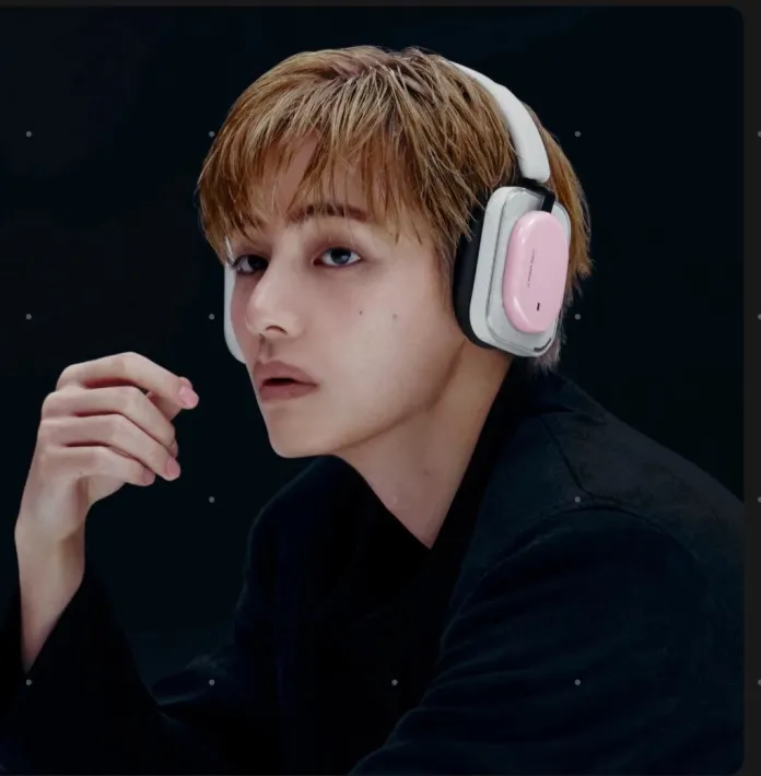 Kim Taehyung with short, light brown hair wearing large, stylish headphones with pink accents, posing thoughtfully against a dark background.