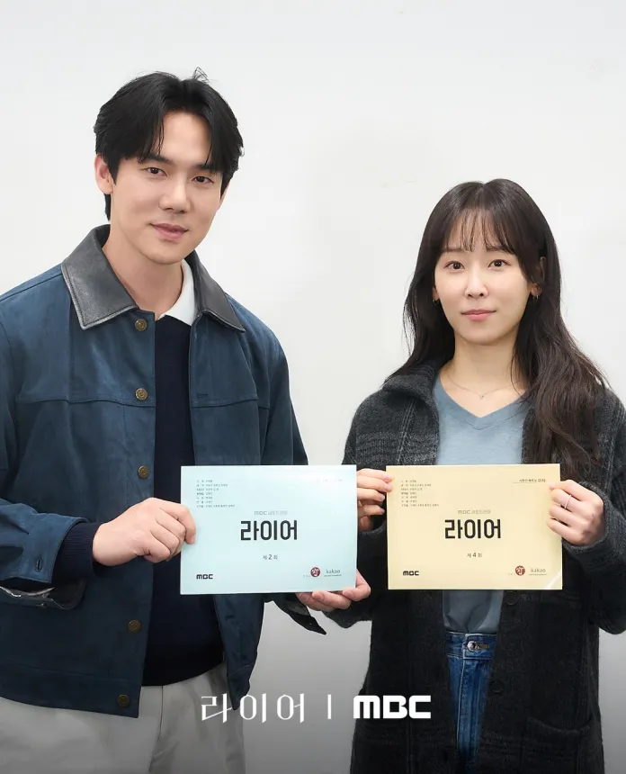 Yoo Yeon-seok and Seo Hyun-jin holding scripts for a drama titled 'Liar' in front of a white background. Yoo Yeon-seok  is wearing a blue jacket and Seo Hyun-jin is in a black cardigan.