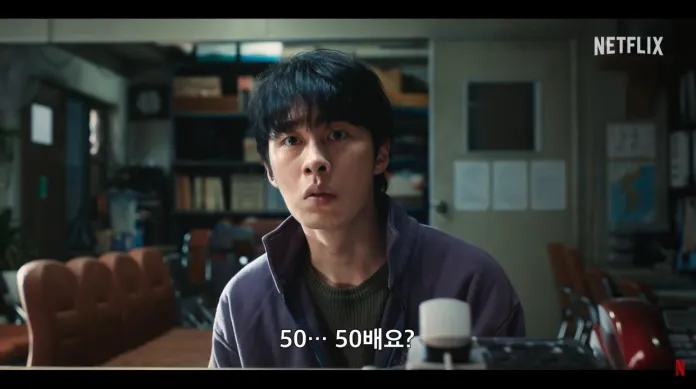 Lee Jae-wook with dark hair, looking surprised and confused, sits in an office environment with chairs and shelves in the background; text in Korean reads '50... 50배요?'