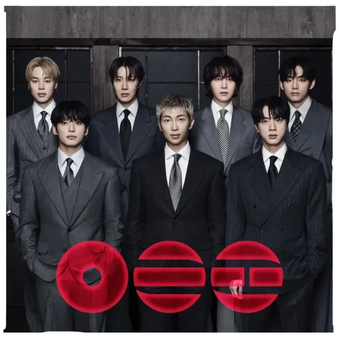 BTS dressed in stylish suits, standing together in front of a dark background with geometric patterns and a bold red logo at the bottom.