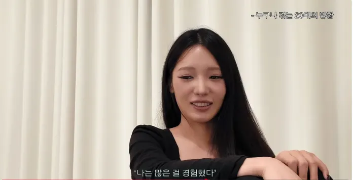 Roh Jisun with long dark hair is sitting and smiling, wearing a black top, against a backdrop of light-colored curtains. Text in Korean is displayed on the image.