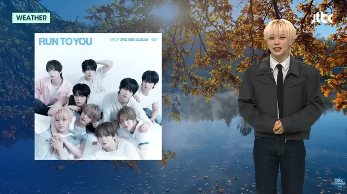 Cha Woongki stands in front of a scenic background with autumn leaves and a lake, next to an album cover titled 'RUN TO YOU' from the group AHOF, featuring nine members posing together.