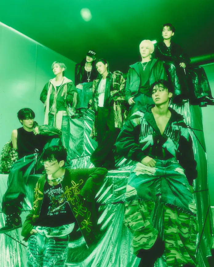 ATEEZ members posing together on metallic surfaces with a greenish lighting, showcasing a mix of fashion styles, including streetwear and casual attire.