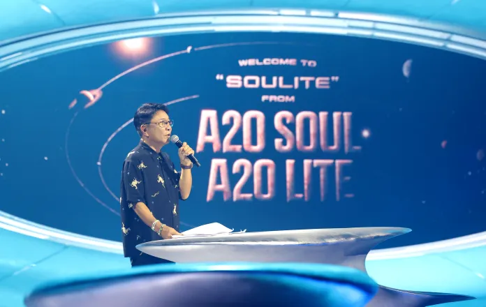 Lee Soo man speaking into a microphone on stage at an event titled 'SouLite' from A20 Soul and A20 Lite, with a visually engaging background.