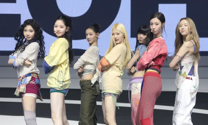 TUIDE members posing together on stage, wearing colorful and casual outfits, with playful expressions and arms crossed.