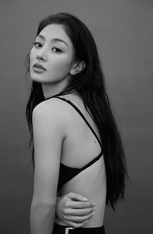Jihyo with long hair, looking over her shoulder, wearing a backless top, with a soft expression.