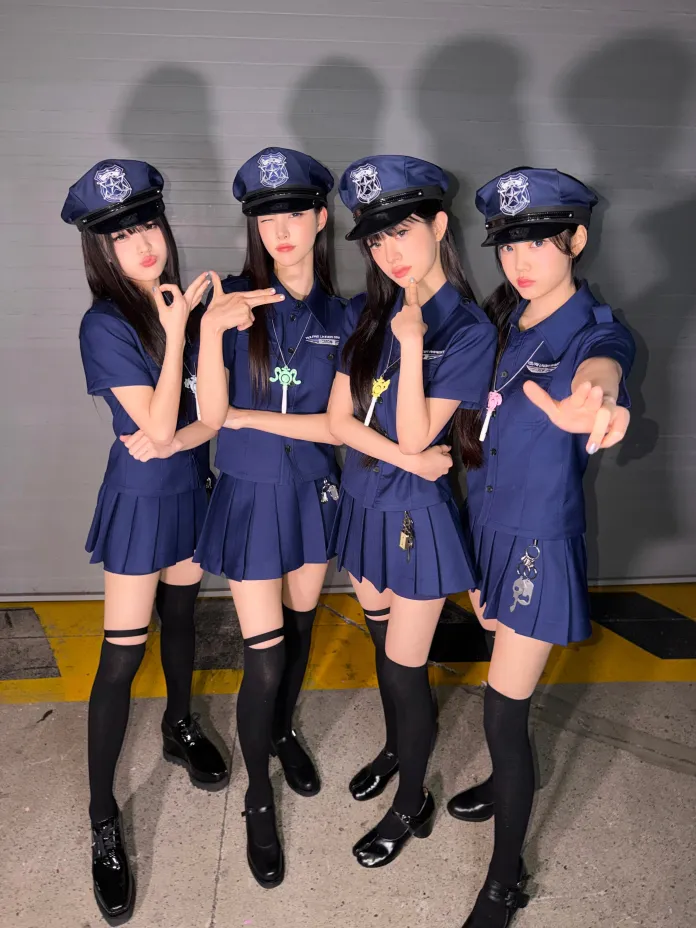 ILLIT members dressed in police-themed outfits with dark blue uniforms and hats, striking playful poses indoors.