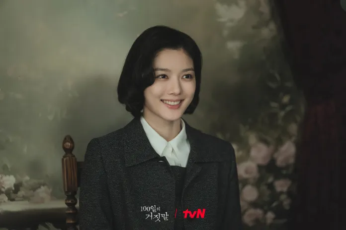 Kim You-jung with short, wavy black hair smiles warmly, wearing a dark jacket over a white shirt. The background features a soft floral painting.