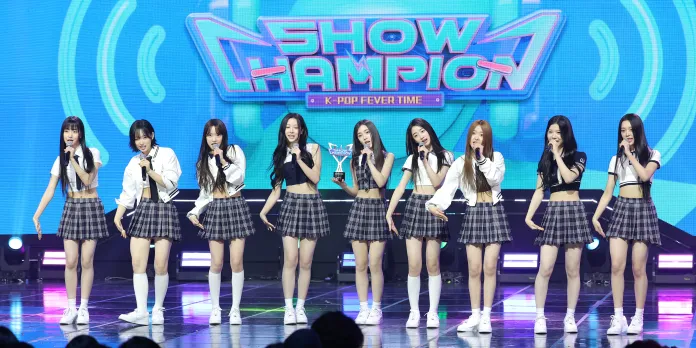 A2O LITE  performing on stage during a music show called 'Show Champion,' wearing matching plaid skirts and white tops.
