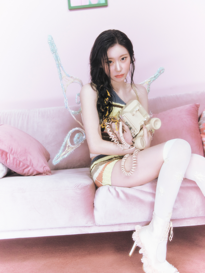 Chaeryeong seated on a pink sofa, wearing a colorful dress and thigh-high stockings, holding a vintage rotary phone. She has butterfly wings and appears to have an expressive, contemplative look.