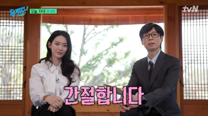 Shin Min-a sitting in a traditional Korean setting, with wooden screens in the background. The woman is wearing a white blouse and the man is in a suit with glasses. The text '간절합니다' appears prominently in pink.