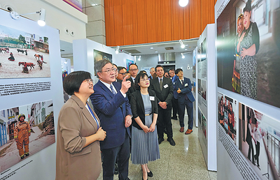 Warner Cheuk Wing-hing (front, center), Hong Kong's deputy chief secretary for administration, accompanied by Liu Weiling (front, right), deputy editor-in-chief of China Daily, visits the Changing Asia photo exhibition in Shenzhen, Guangdong province, on Monday. ADAM LAM/CHINA DAILY