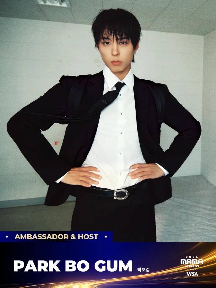 Park Bo-gum wearing a black suit and white shirt poses confidently with his hands on his hips in a minimalistic white room. Text at the bottom identifies him as Park Bo Gum, Ambassador and Host for the 2026 MAMA Awards.