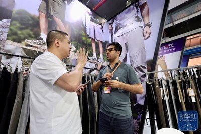 A foreign merchant talks with an exhibitor during an exhibition held in Shishi Clothing City of Quanzhou, Fujian Province in southeast China on April 18, 2026. (Xinhua/Jiang Kehong) (PRNewsfoto/Xinhua Silk Road)