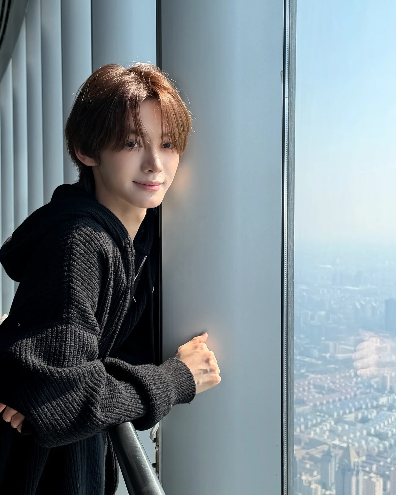 블랙 니트 후디 | 고층 빌딩 숲을 배경으로 부드러운 카리스마를 내뿜는 한진의 창가 샷 /사진=한진 인스타그램