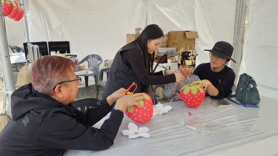 엄마 아빠와 축제장을 찾아 '딸기꽃등' 만들기 체험을 하고 있는 어린이/사진=유경훈 기자